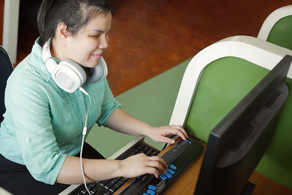 Blind person using a computer with a keyboard for the blind.